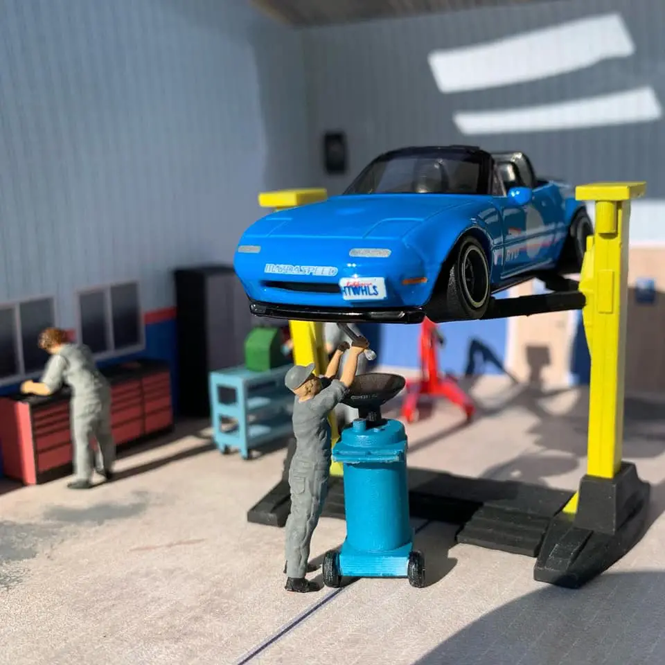 blue hot wheels miata on lift in tiny garage